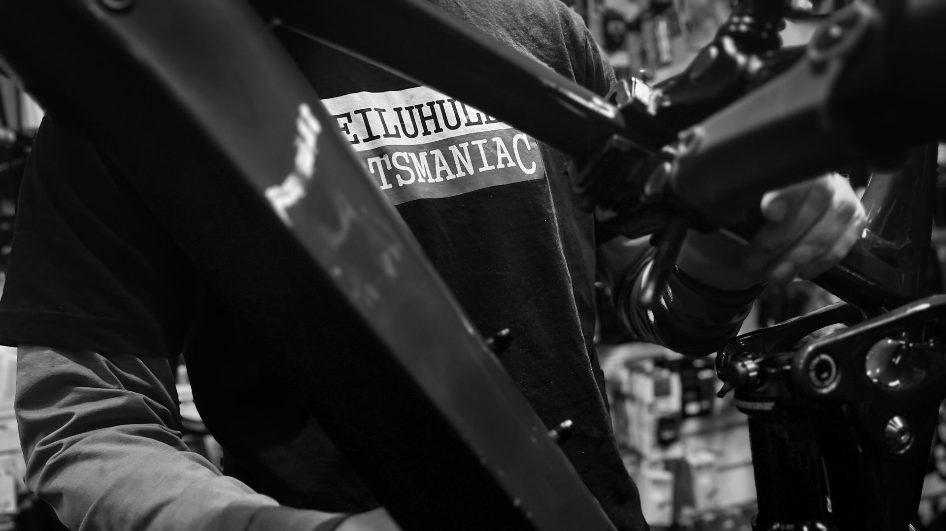 A man is working on a bicycle in a black and white photo.