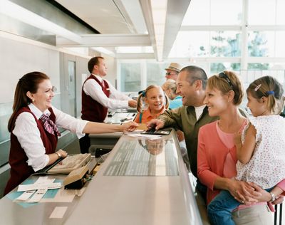 Hotel reception desk with staff helping smiling guests, including a woman holding a child
