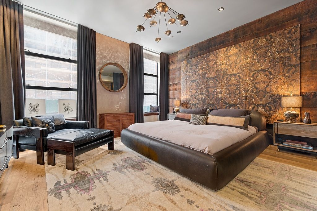 Luxurious bedroom with a large bed, ornate wall, and dark leather furniture.