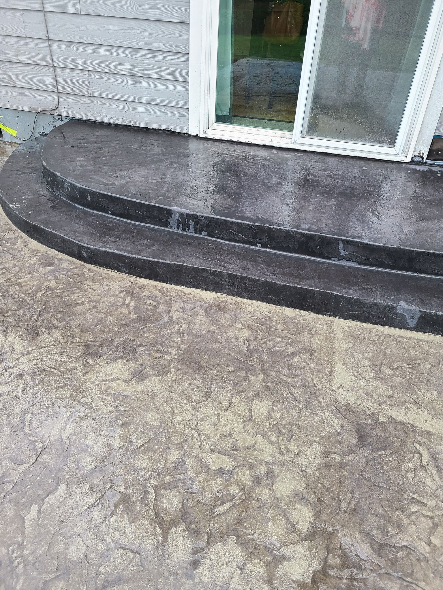 A concrete patio with steps leading up to a door.
