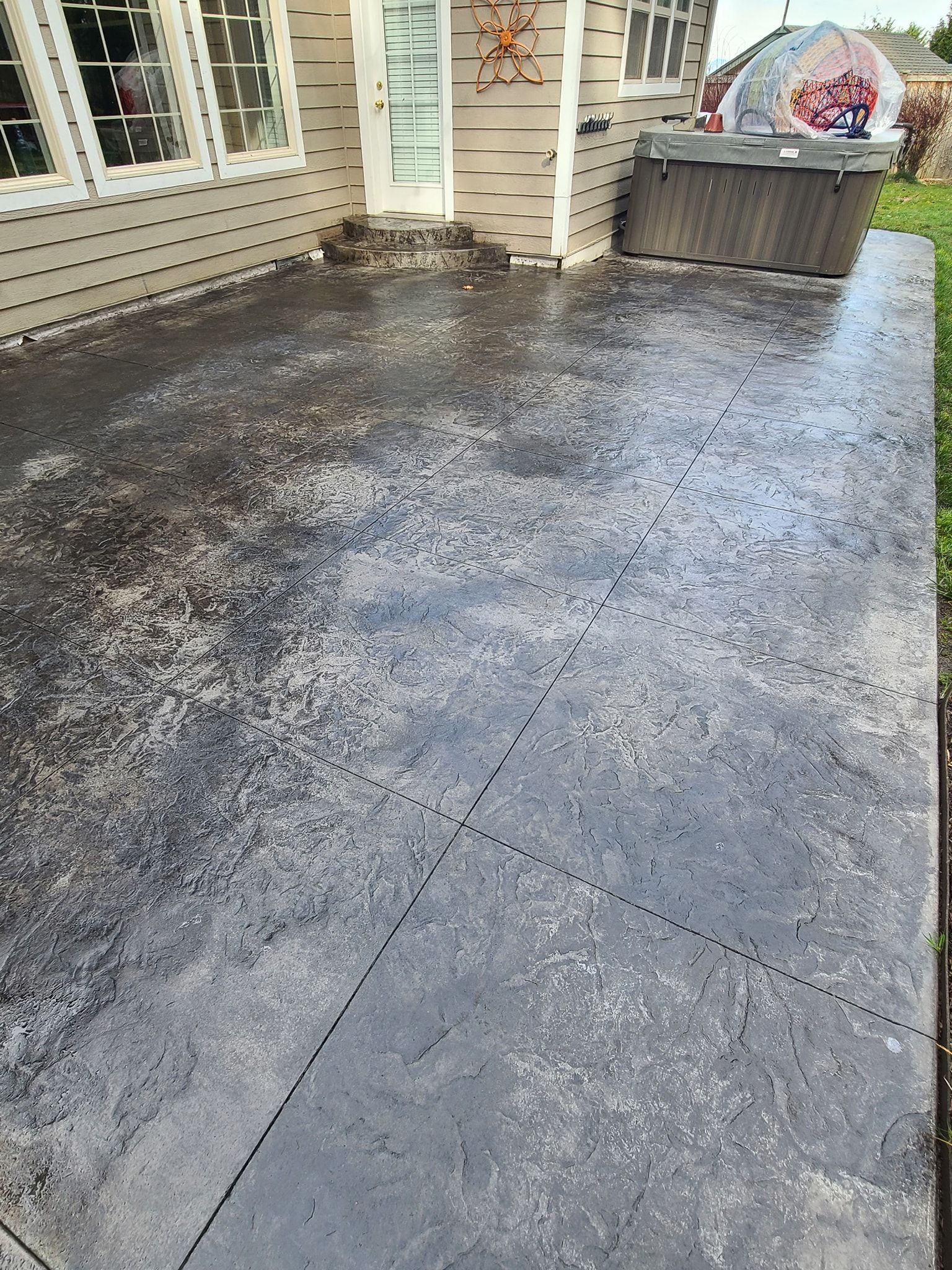 A concrete patio with a hot tub in the background.