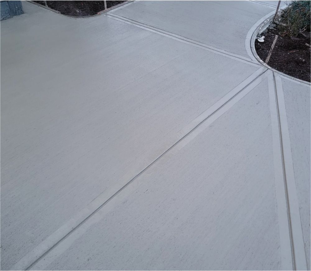 A close up of a concrete driveway with a tree in the background