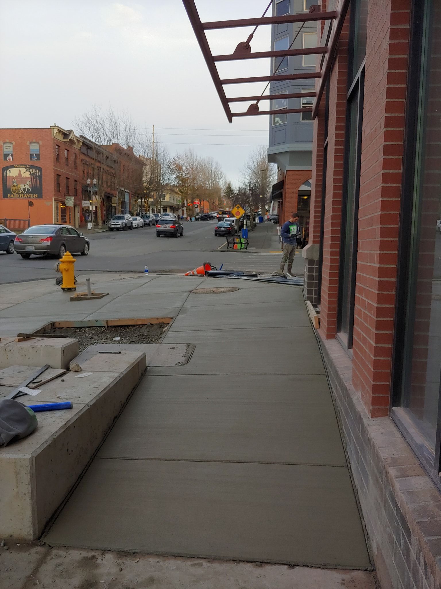 A sidewalk is being built in front of a brick building.
