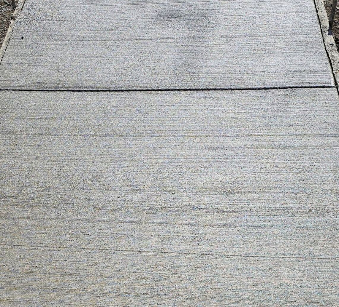 A close up of a concrete sidewalk with a brick pattern.