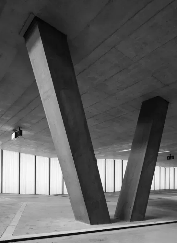 A black and white photo of a parking garage with columns and windows.