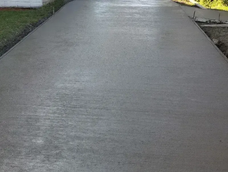 A concrete driveway is being built next to a house.