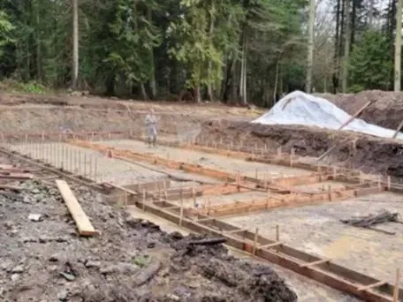 a concrete foundation with a lot of dirt and trees in the background of Bellingham Washington.