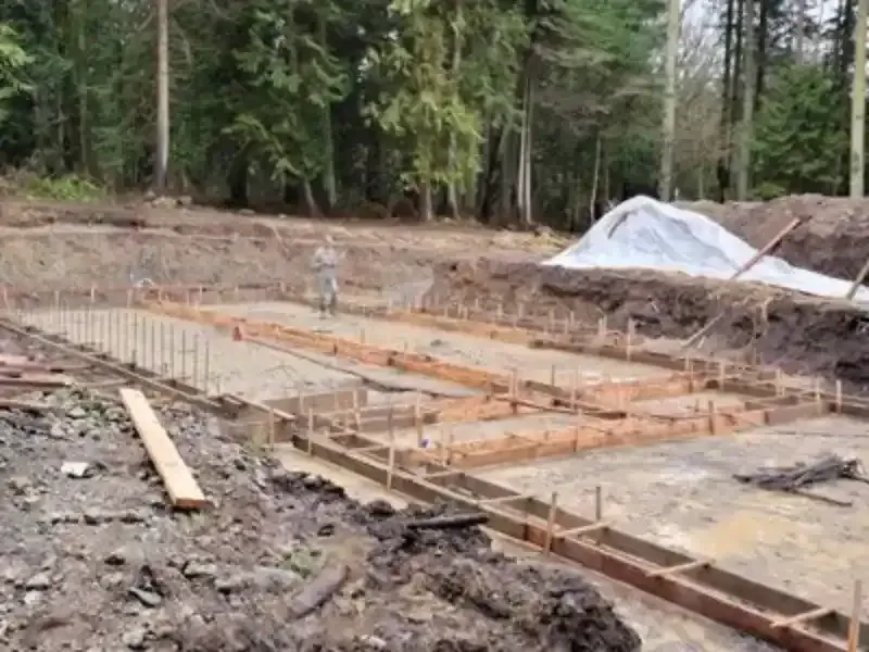 A construction site with a lot of dirt and trees in the background.