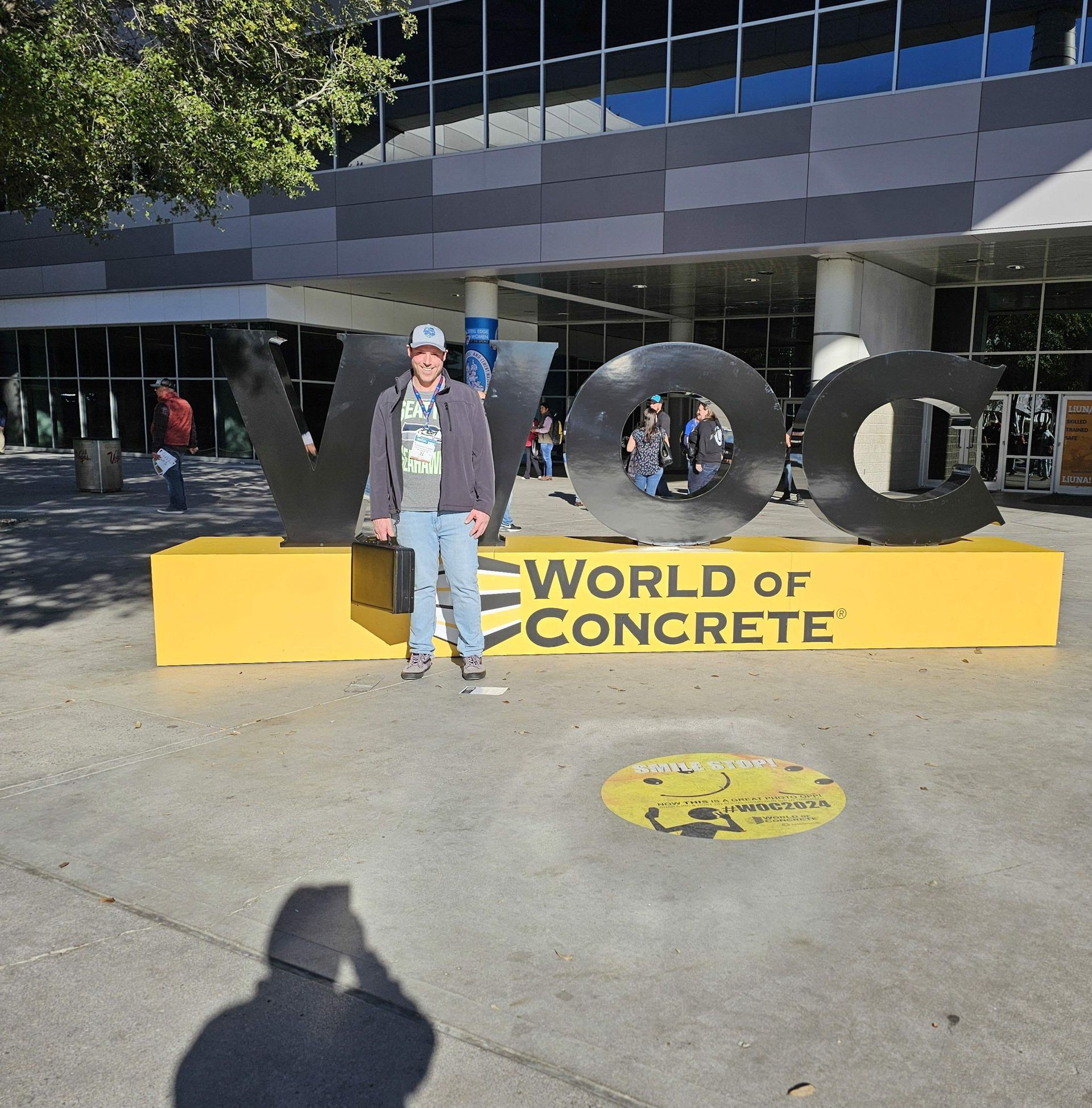 A man stands in front of a world of concrete sign