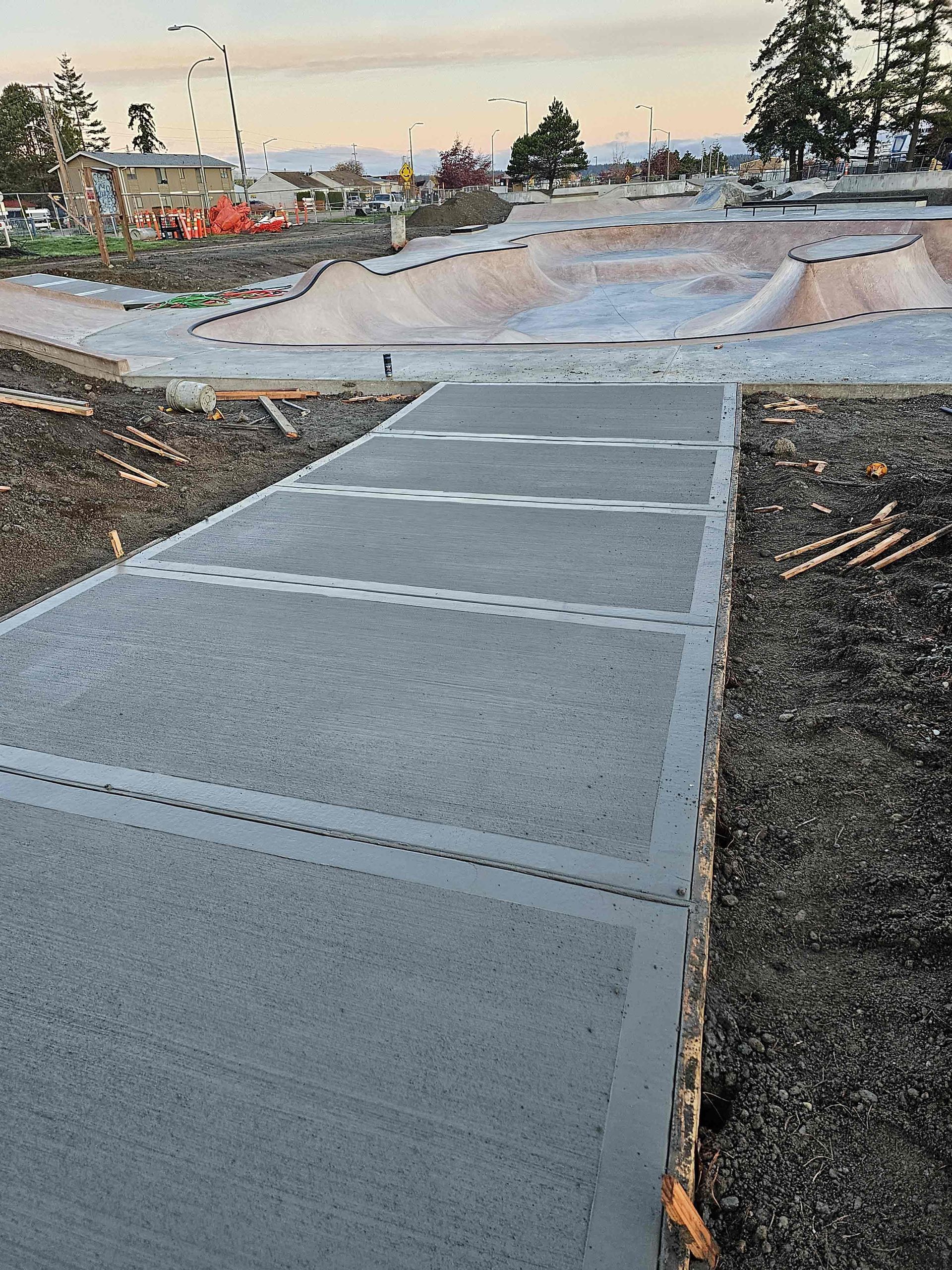 A concrete walkway is being built in a park with a ferris wheel in the background.