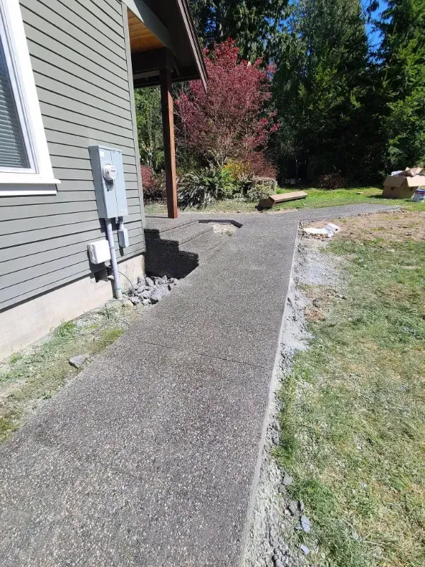 a concrete sidewalk leading to a house with trees in the background in Bellingham Washington.