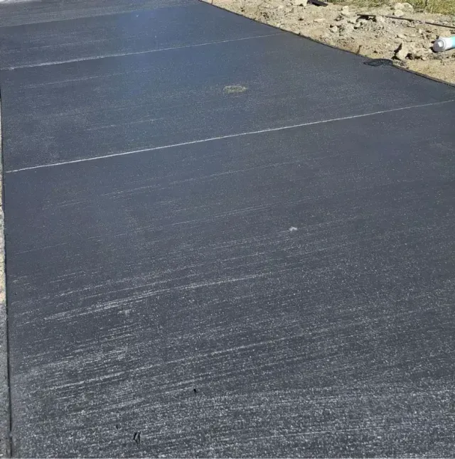 A concrete driveway leading to a purple house and a blue house.