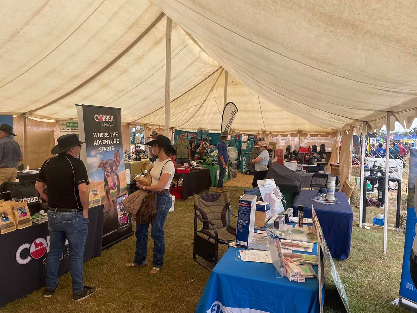 A Group Of People Are Standing Around Tables Under A Tent — TGT Pty Ltd in Mareeba, QLD
