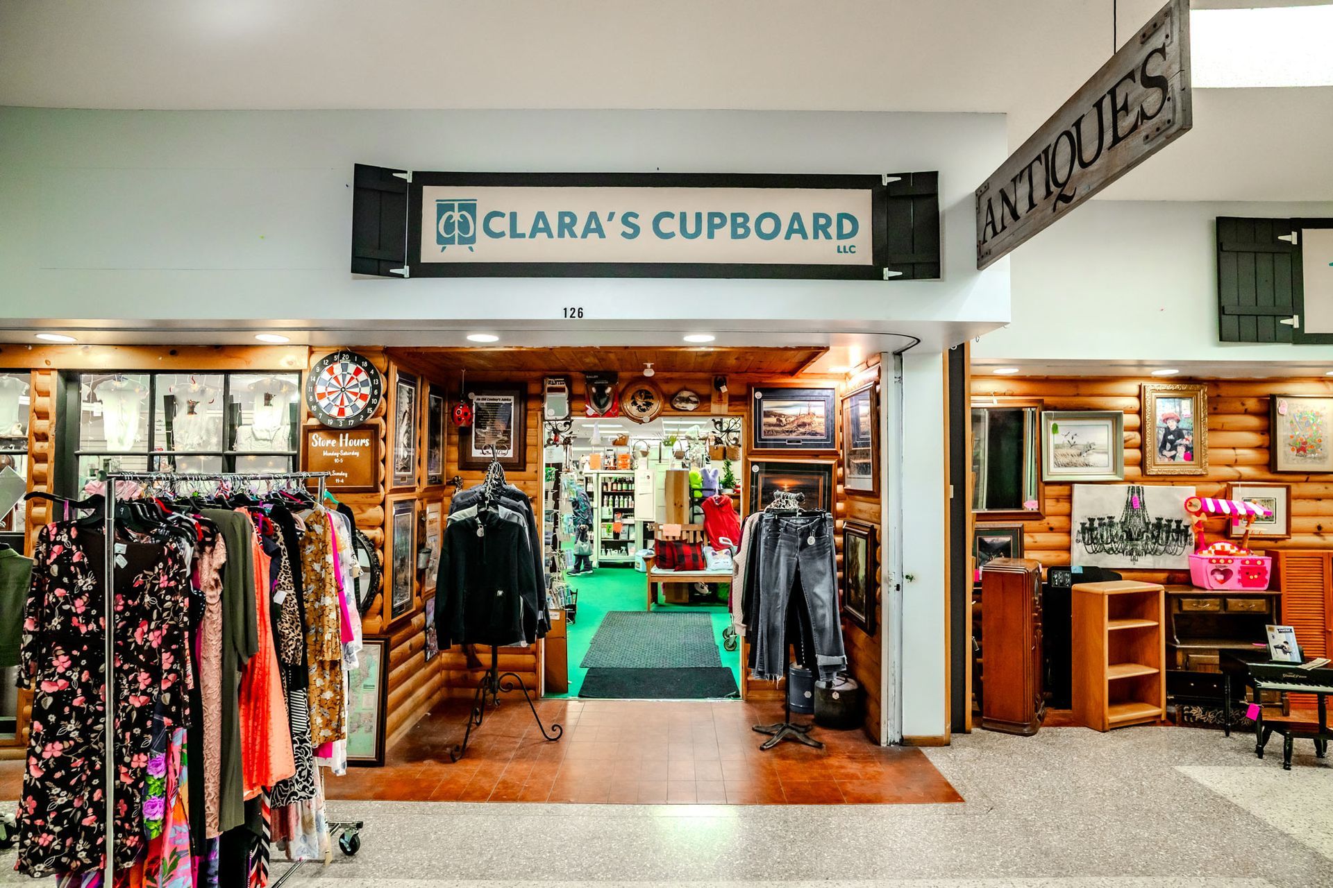 Clara's Cupboard antique store entrance; clothing racks on the left, wood interior, 