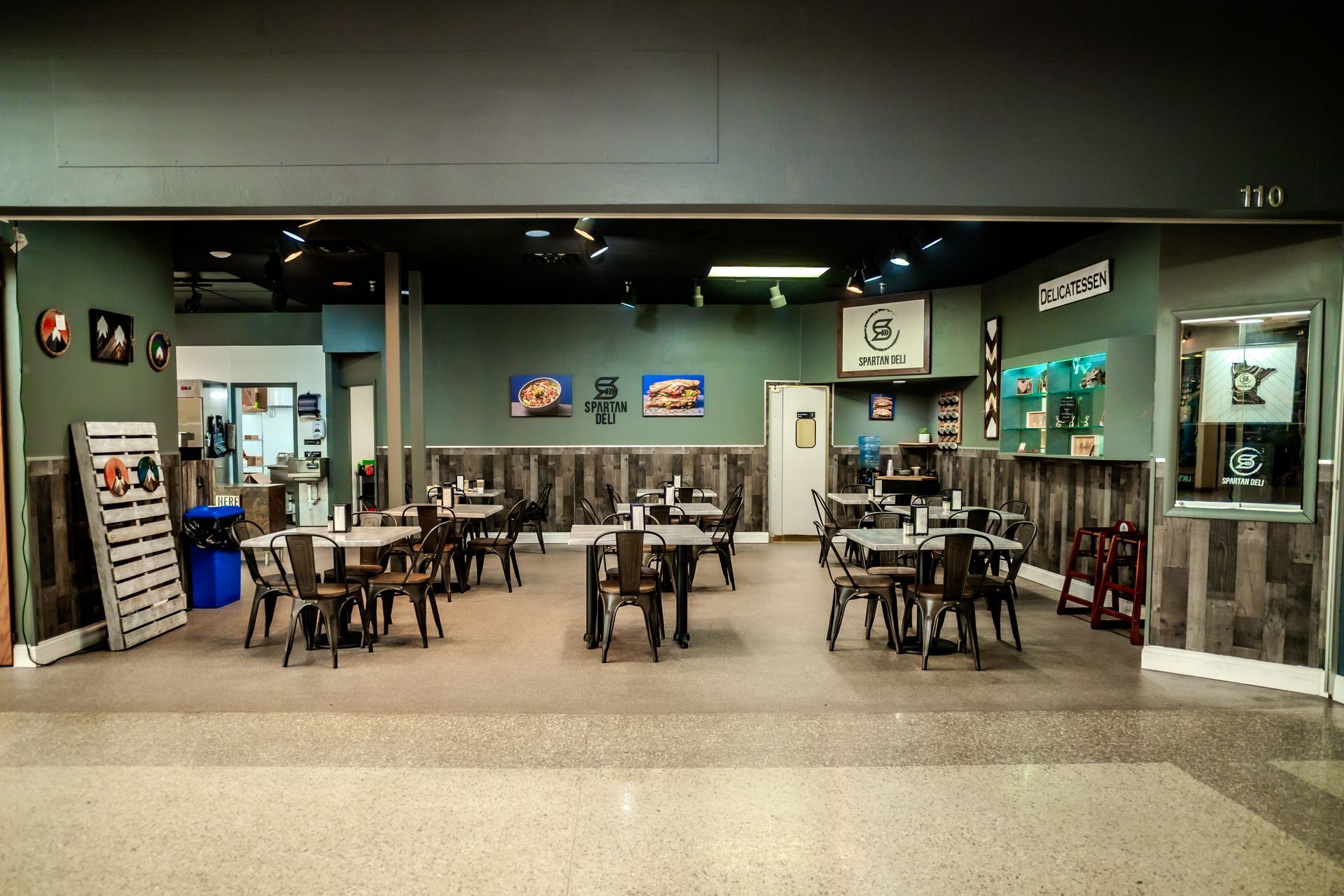 Restaurant interior with tables, chairs, and wall decor. Teal walls, wood accents, and a dark ceiling.