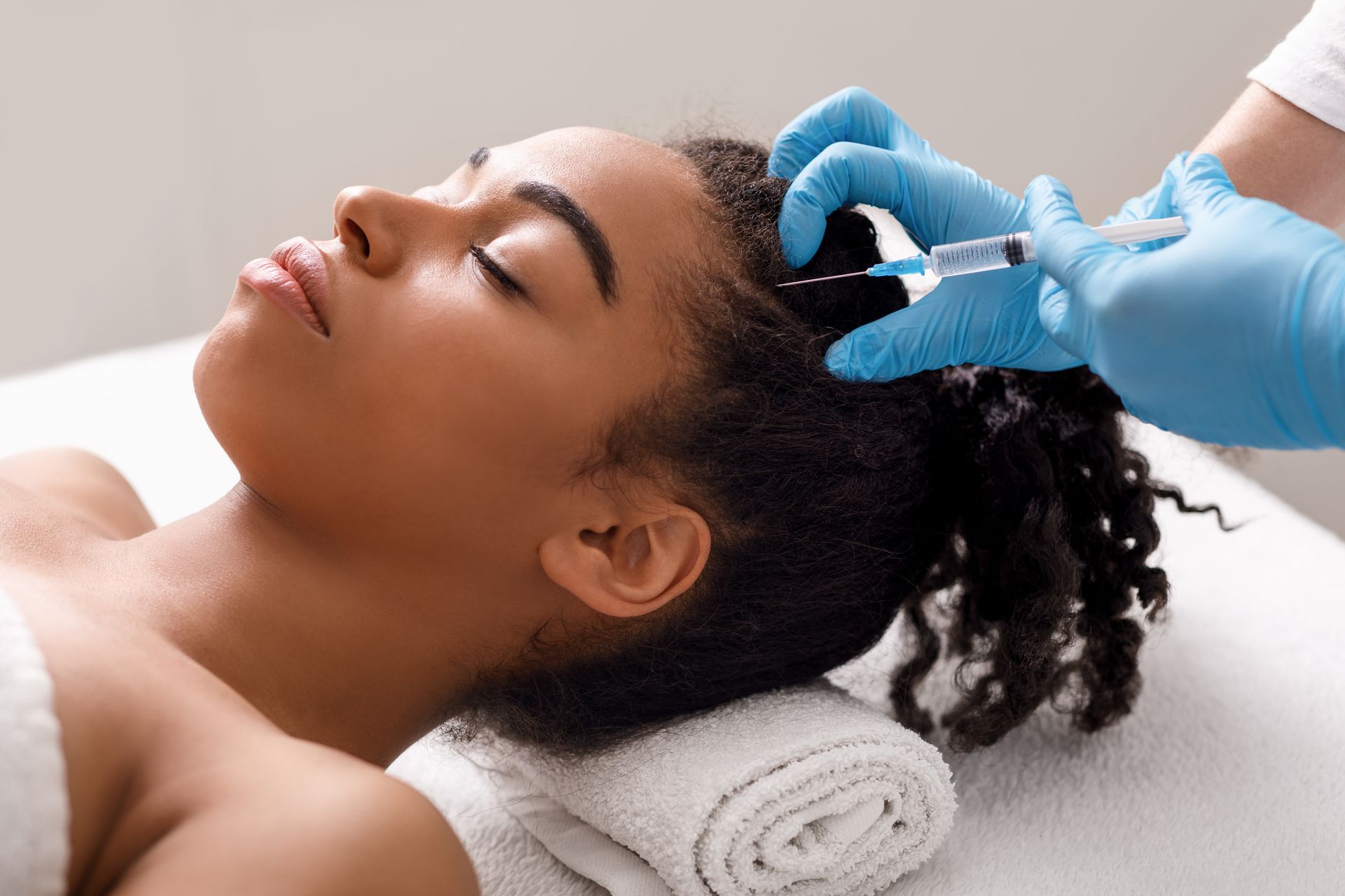 A woman is getting a botox injection in her head.