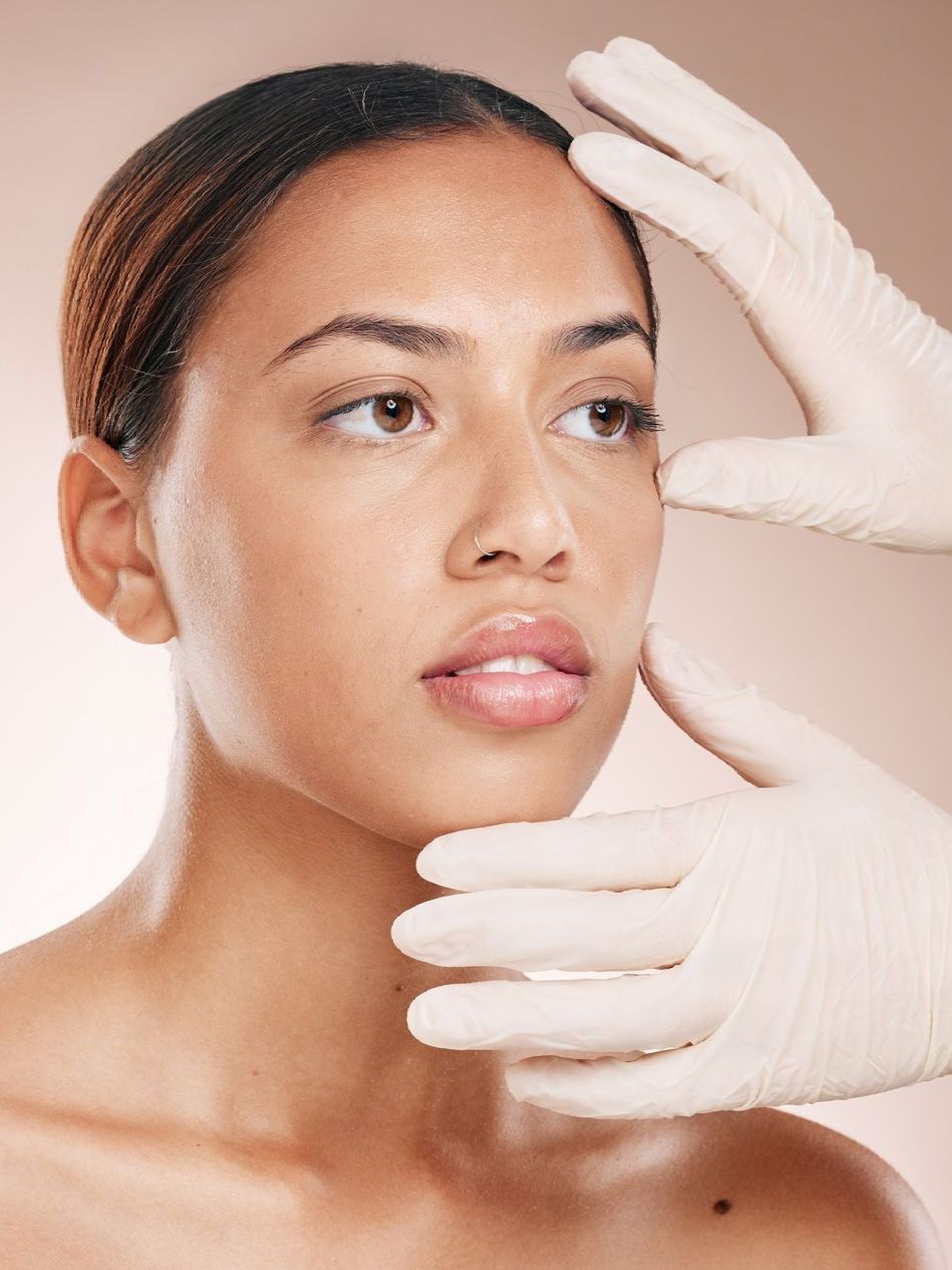 A woman is getting her face examined by a doctor wearing gloves