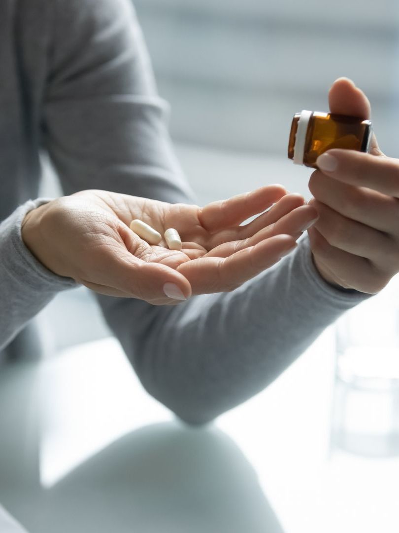 A woman is holding a bottle of pills in her hand