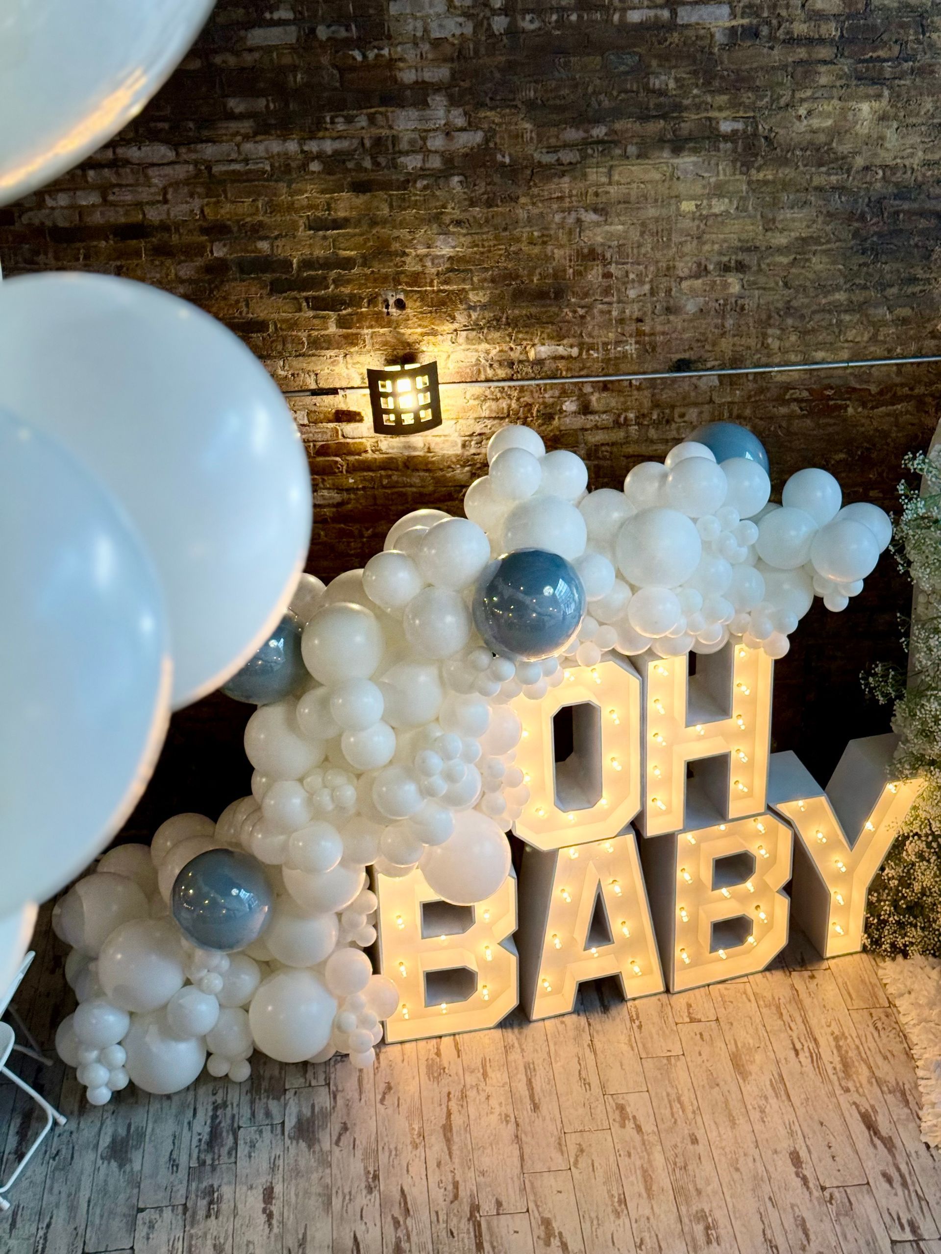A sign that says oh baby is surrounded by balloons.