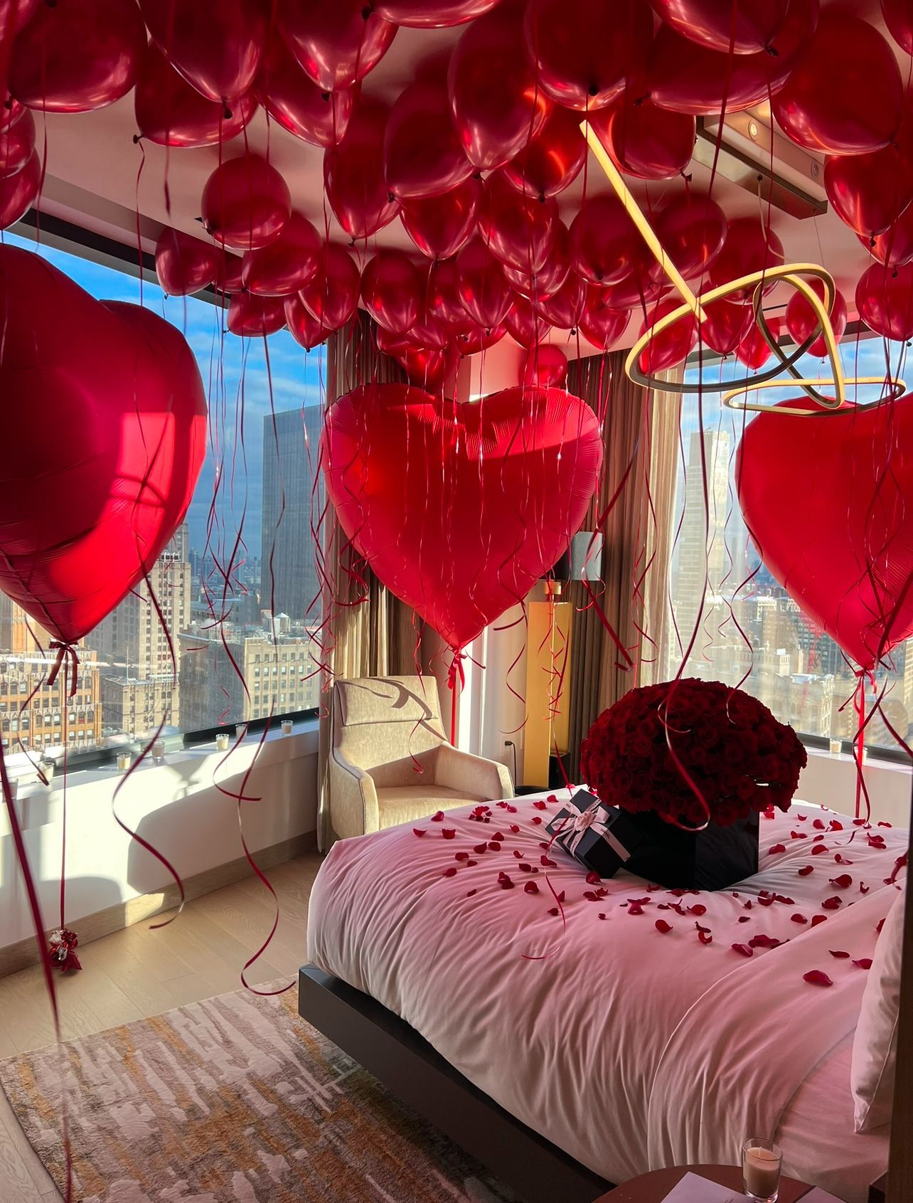 A bedroom decorated for valentine 's day with balloons and rose petals.