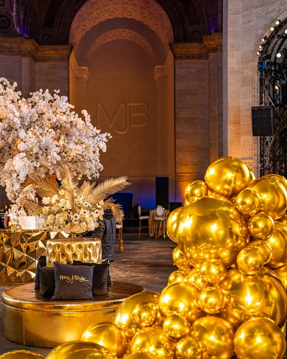 A bunch of gold balloons are stacked on top of each other in a room.