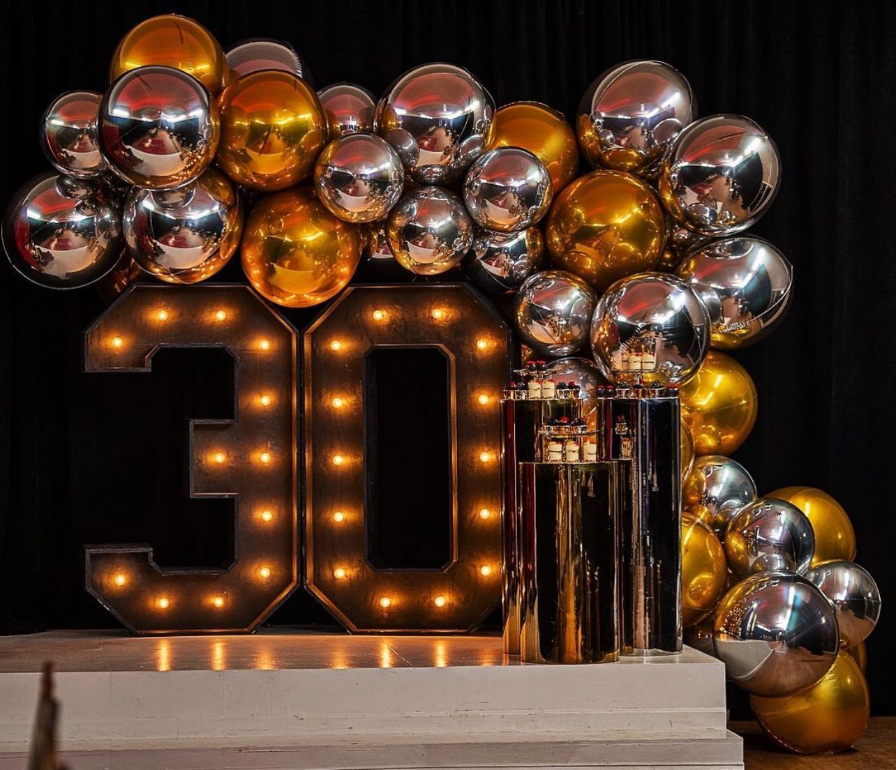 A large number 30 is surrounded by gold and silver balloons.