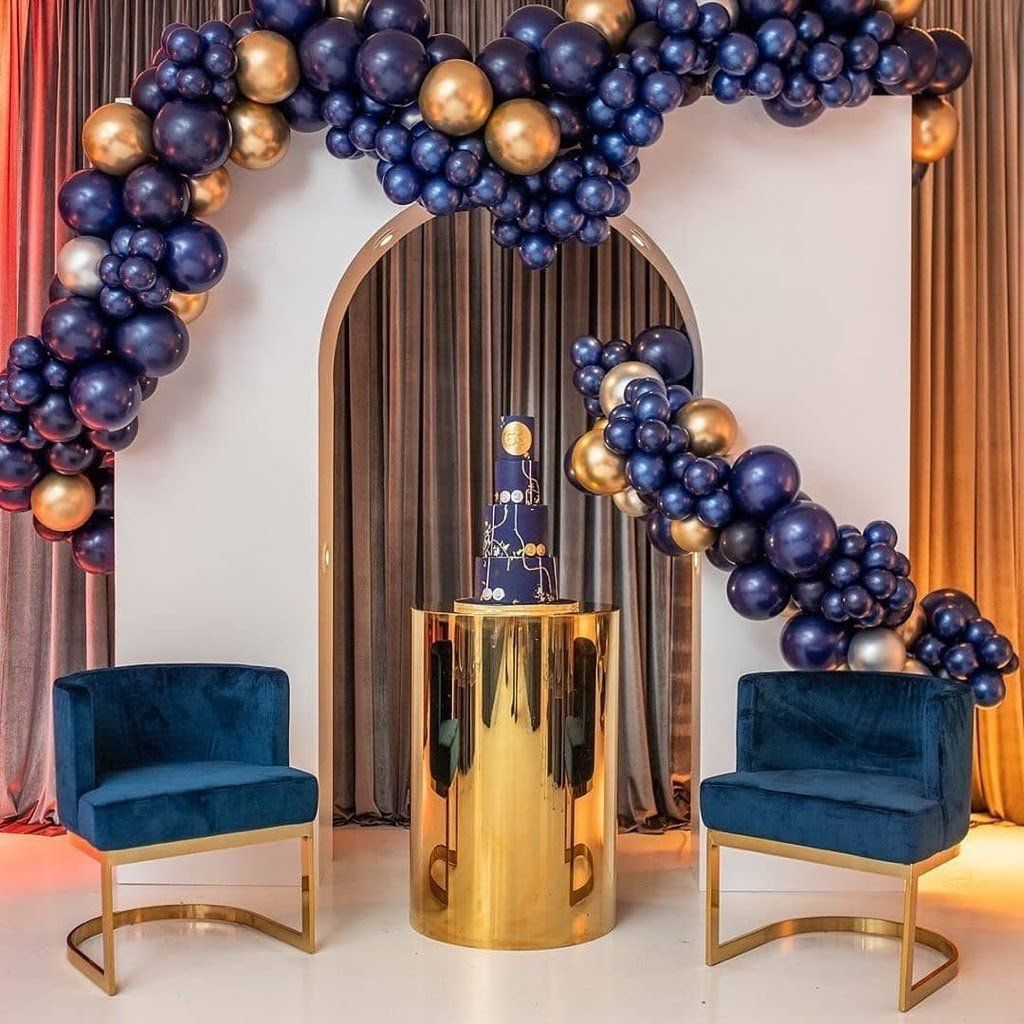 A room decorated with blue and gold balloons and two chairs.