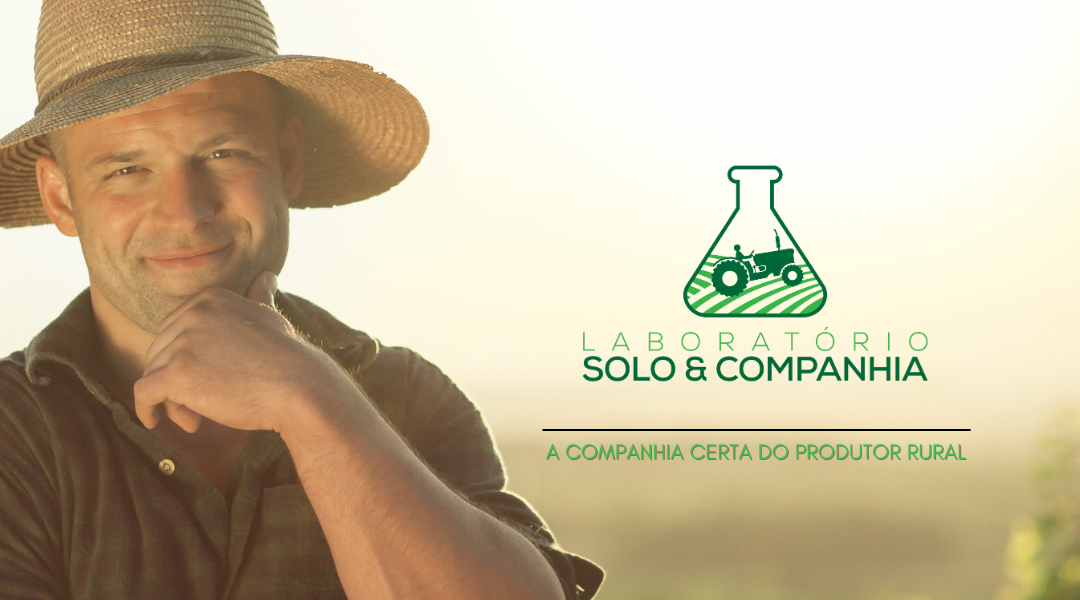 Um homem usando um chapéu de palha está parado em frente ao logotipo de um laboratório.