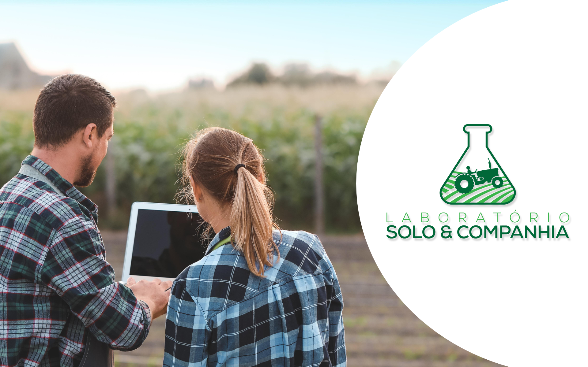 Um homem e uma mulher estão olhando para um laptop em um campo.
