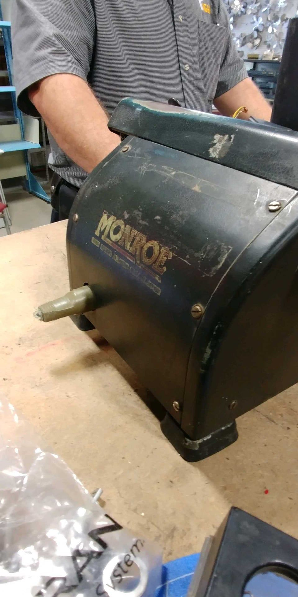 A man is sitting at a table working on a machine.