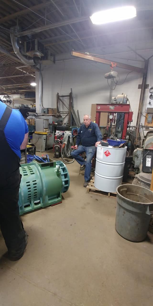 A man is sitting on a barrel in a garage.