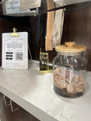 Counter display with a jar of fabric, accessories, and a sign.