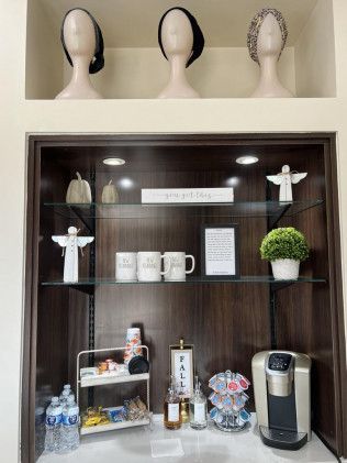 Coffee bar with accessories displayed on shelves and mannequin heads above.