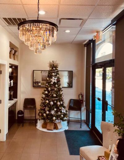 Reception area with a Christmas tree, chandelier, chairs, and a door to the outside.