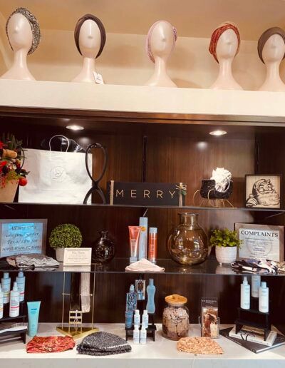 Display of wigs and beauty products on shelves.  Mannequin heads with wigs, retail display with items.