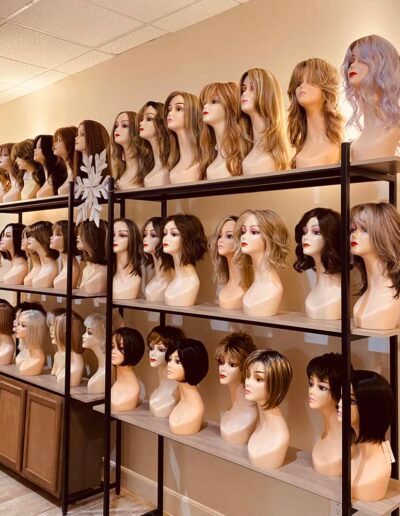Wigs on display on shelves in a well-lit store, showcasing various styles and colors.
