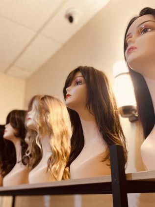 Mannequin heads with wigs on display; shop interior.