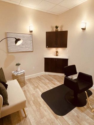 Salon interior with chair, cabinets, artwork, and light-colored wood flooring.