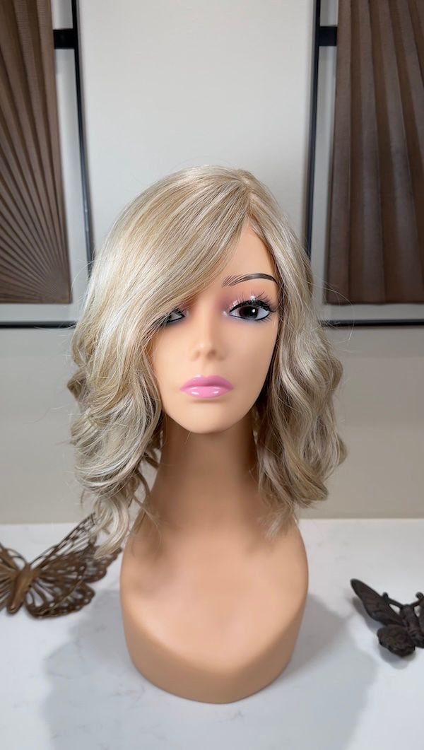 Mannequin head wearing a blonde wig with wavy layers, set against a neutral background.