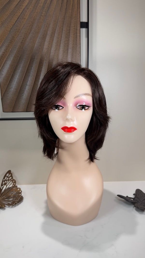 Brown wig on a mannequin head with red lipstick and pink eye shadow.