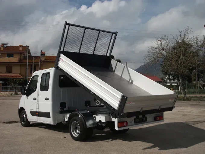 Autocarro ribaltabile bianco con cassone rialzato parcheggiato all'aperto sotto un cielo nuvoloso.