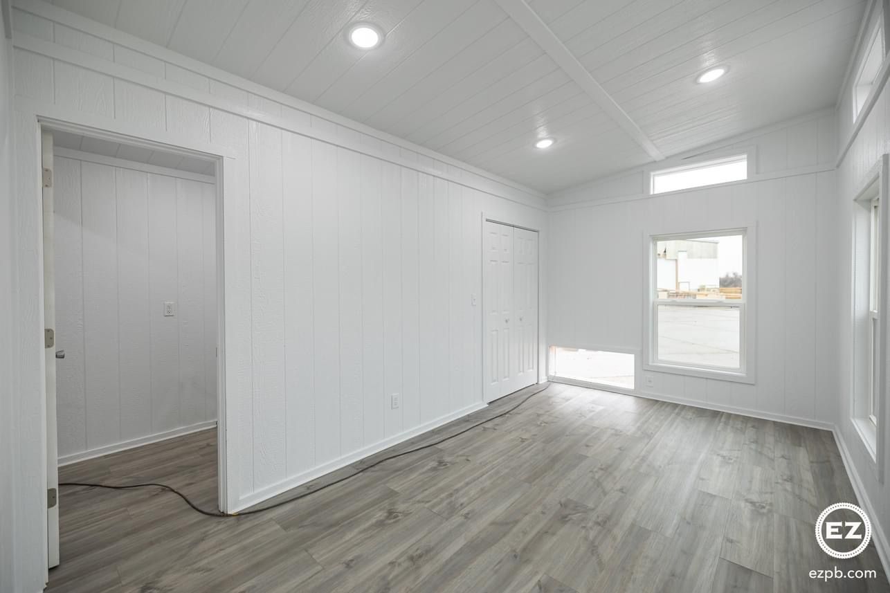 A large empty room with hardwood floors and white walls.