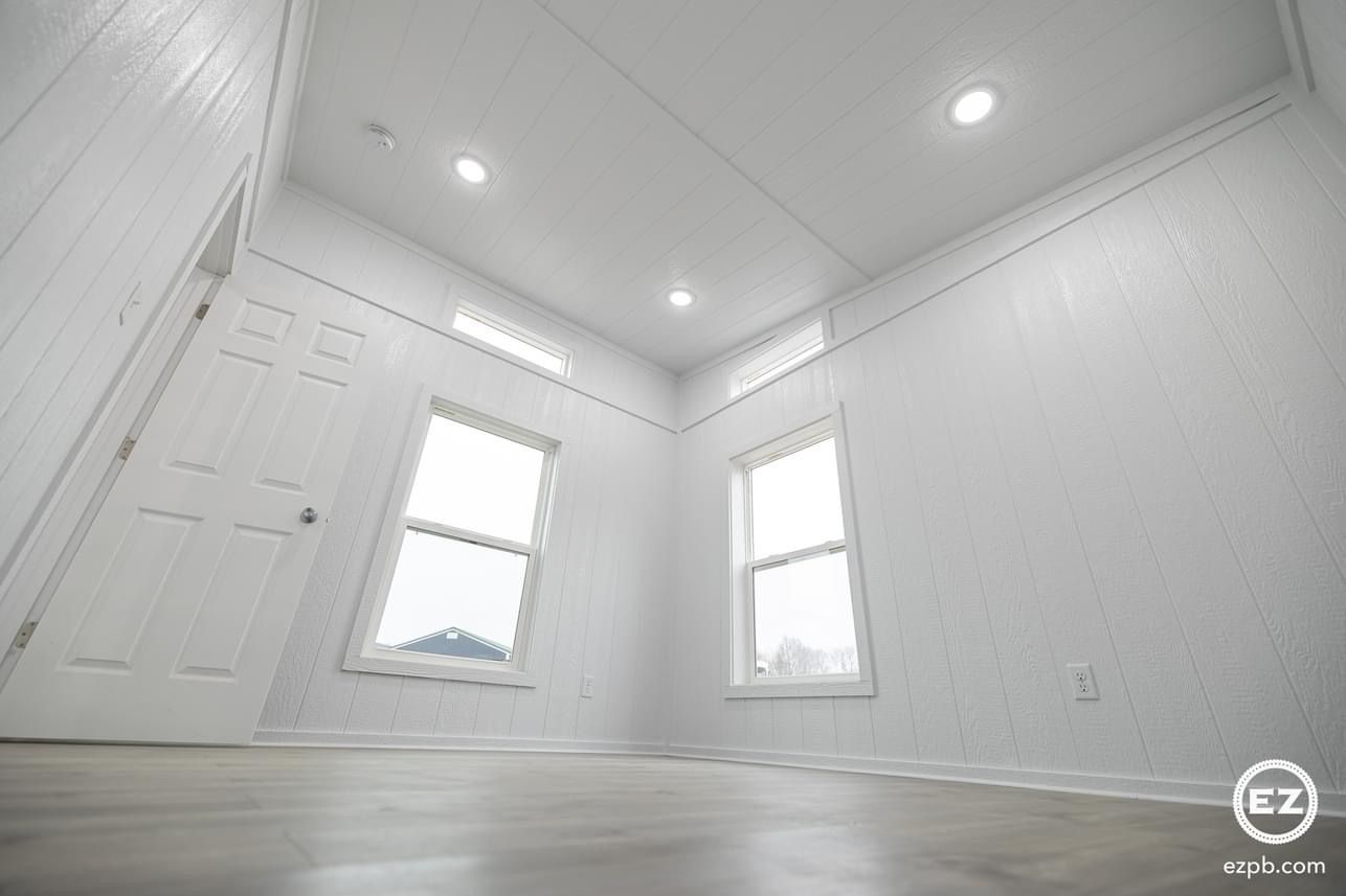 An empty room with two windows and a door.