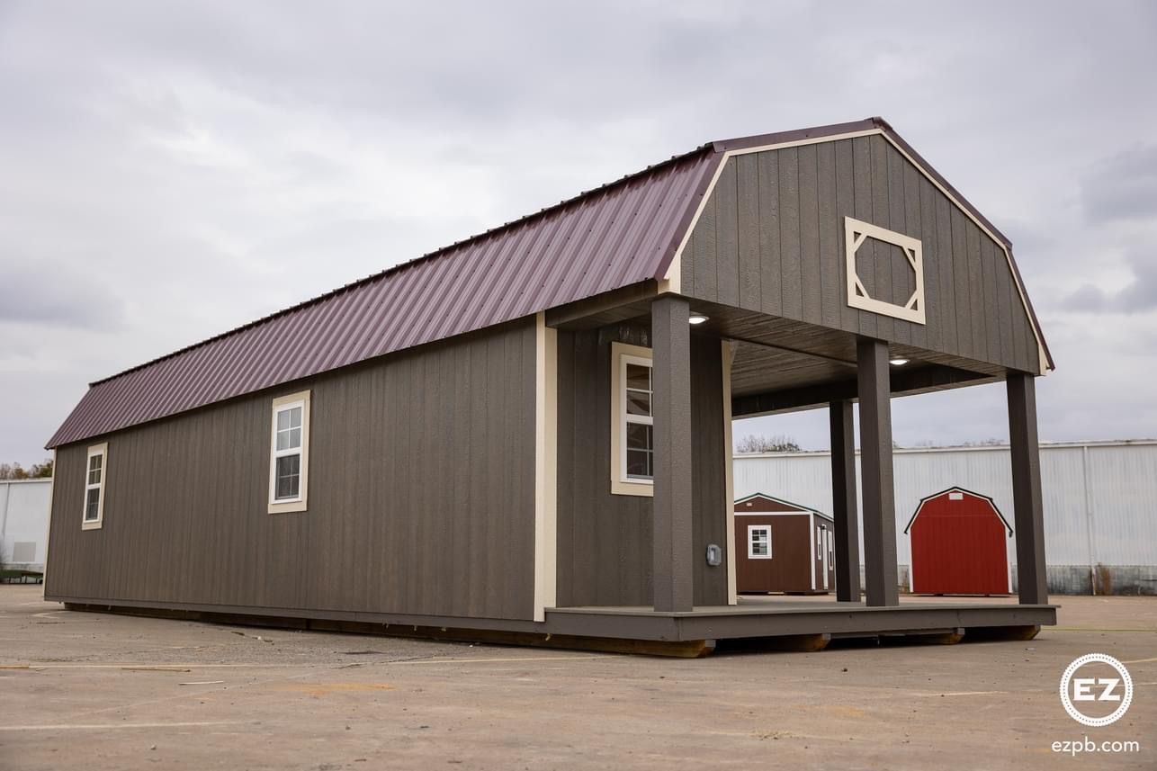 A large barn with a purple roof is sitting in a dirt field.