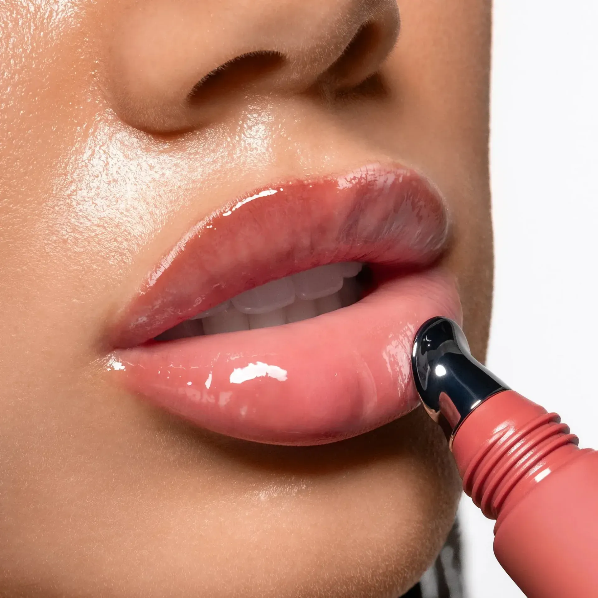 Close-up of lips applying glossy pink lip product with a wand