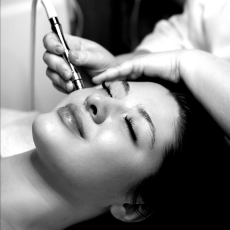 Cosmetic procedure applying a treatment to a woman’s face with a handheld device