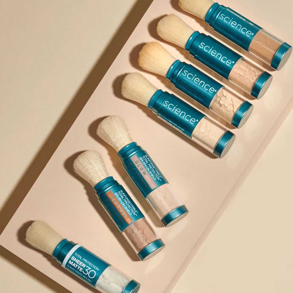 Five teal-and-wood lipstick tubes arranged diagonally in a pink tray.