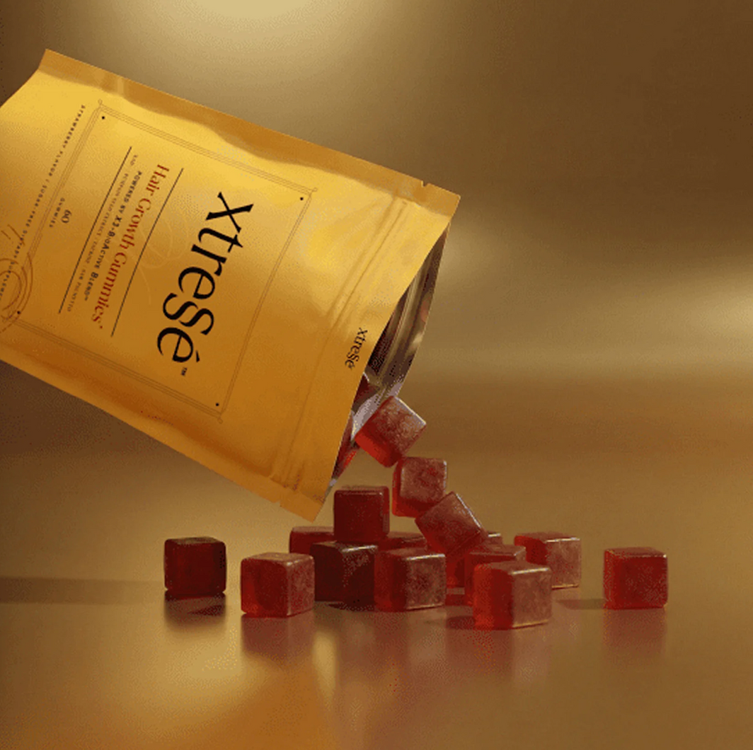 Yellow X-trese bag spilling red gummy cubes onto a warm beige surface