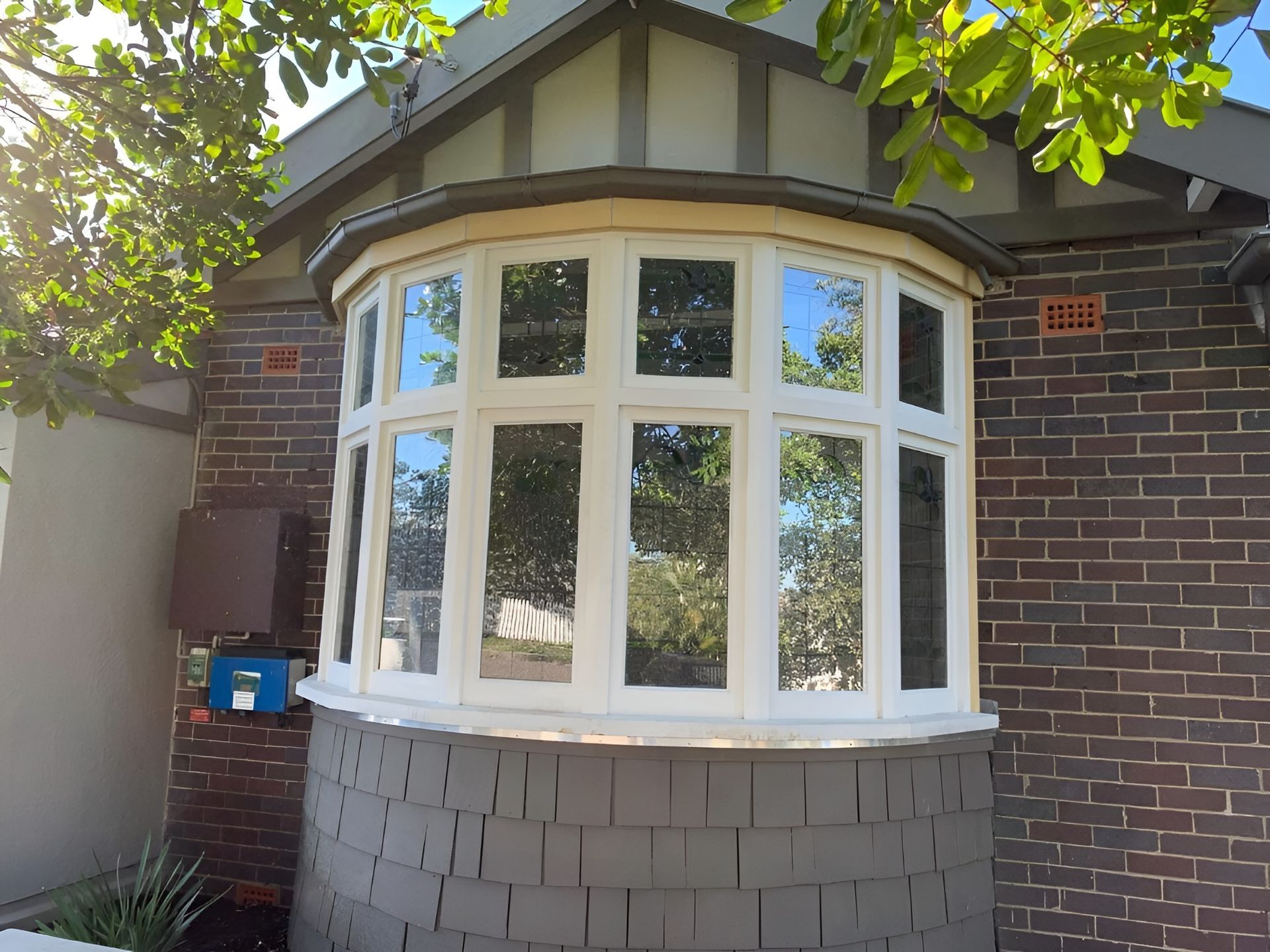 White Bay Window on A Brick House with Grey Shingles and Leafy Tree Branches Overhead — Fineworx Joinery in Warnervale, NSW