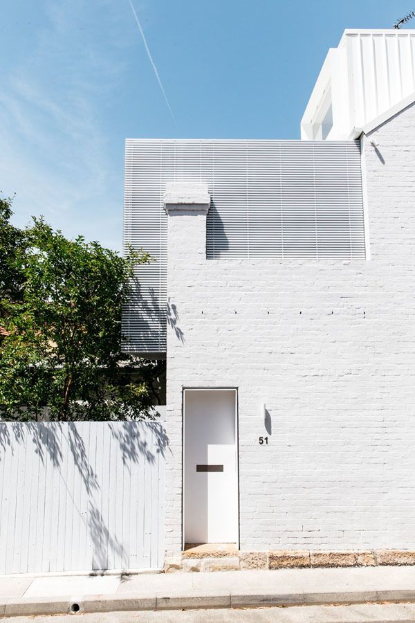 Minimal white modern house facade with a small door, window, and tree beside a white fence under blue sky — Fineworx Joinery in Warnervale, NSW